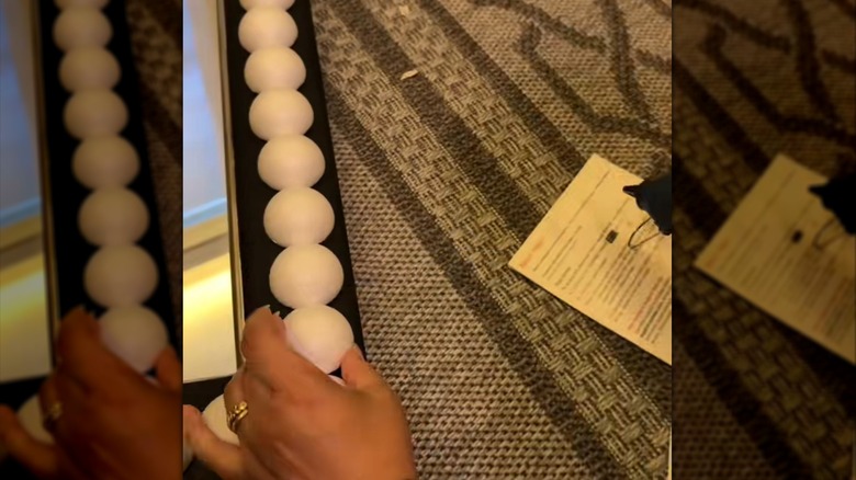 Person adding half moon Styrofoam to decorate mirror frame