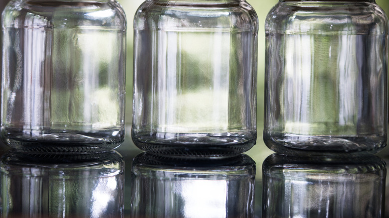 Three empty glass jars on a smooth glass surface
