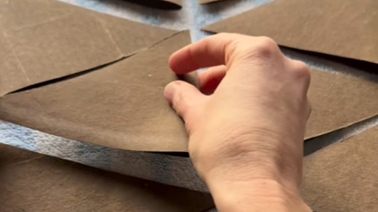 Person folding unfurled toilet paper tubes