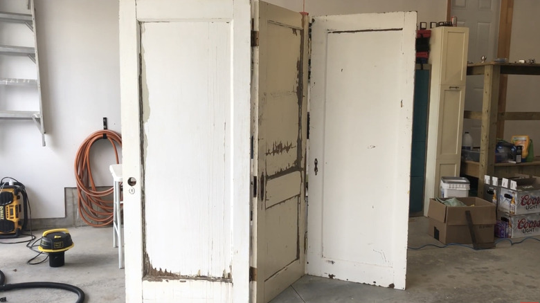 A room divider made out of doors is standing in a garage work area
