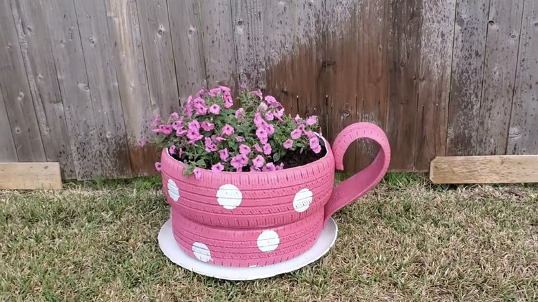 A pink teacup planter made from tires in a backyard