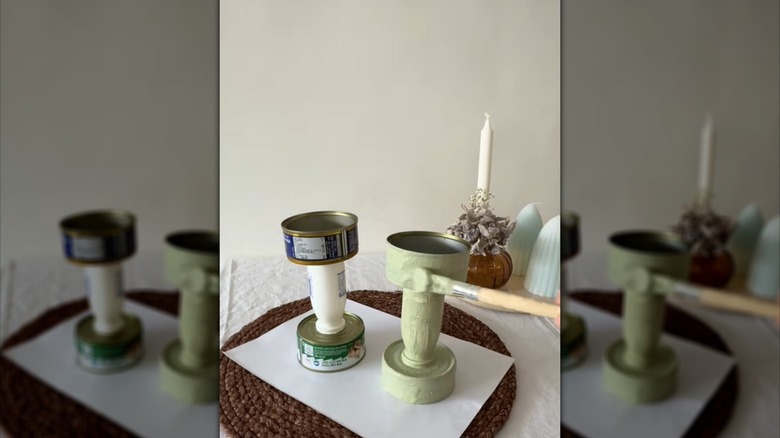 Person painting candle holder made from tuna cans