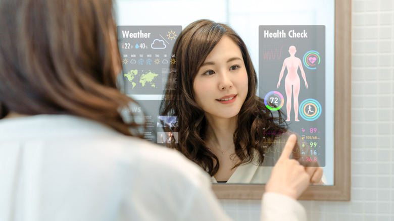 A woman looking at information on a smart mirror