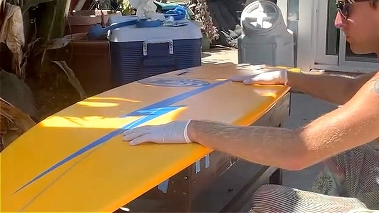 The surfboard top being placed on top of the DIY surfboard coffee table's base