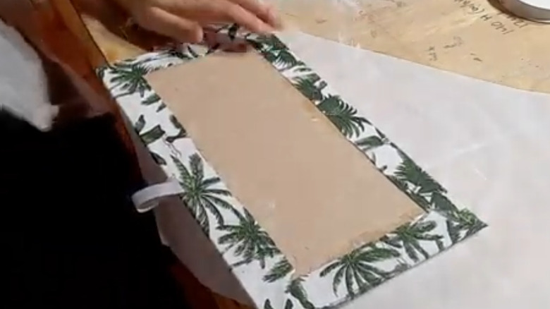 A piece of fabric glued to a medium density fiberboard to make a removable drawer liner