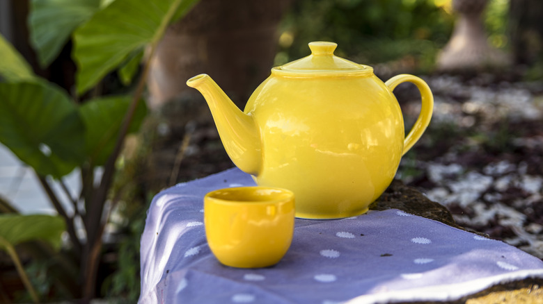 A bright yellow teapot in a garden