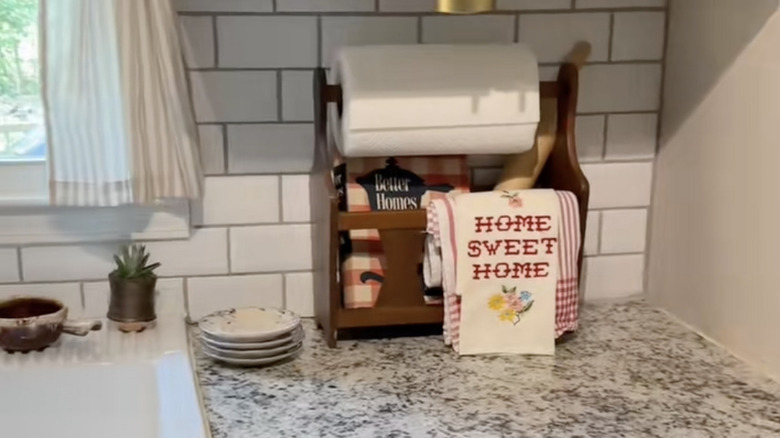 A magazine rack displaying kitchen towels and a cookbook.