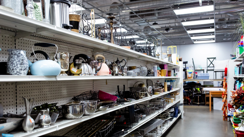 A thrift store aisle with a lot of second hand items, including plant stands.