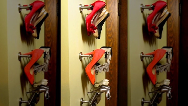 High heels hanging from wall mounted towel racks.
