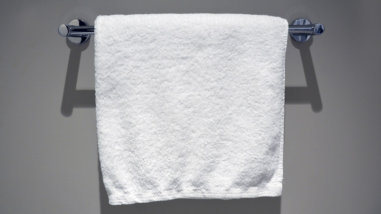A plain white towel on a towel rack in the bathroom.