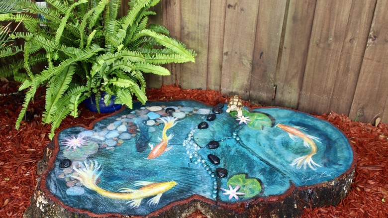 A painted tree stump with a koi pond design.