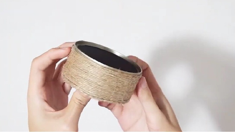 A clean and empty tuna can wrapped in twine.