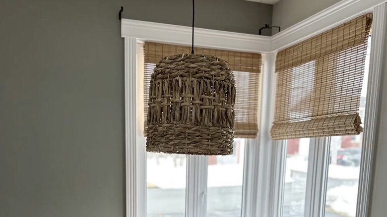 A pendant light made from rope and a wicker basket hangs in the corner of a kitchen.