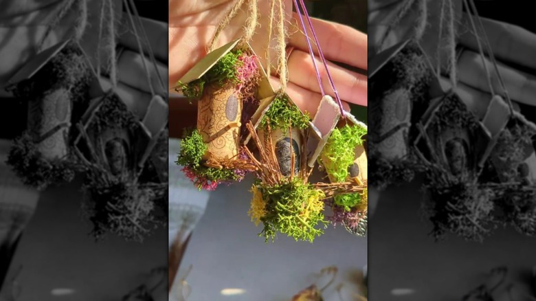 a hand holding three miniature decorative cork birdhouses