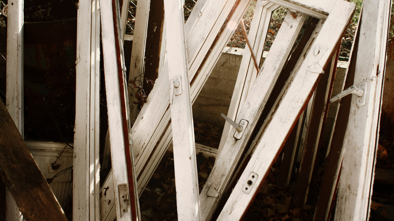 Old wooden window frames are shown leaning together.