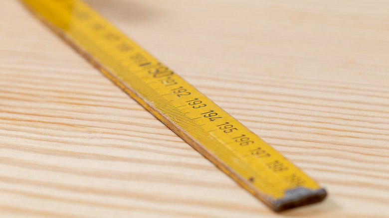 A yellow yardstick lies on a wooden surface.