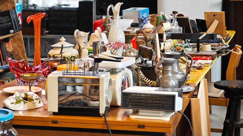 A whole lot of vintage appliances and décor items on a table at a thrift store.
