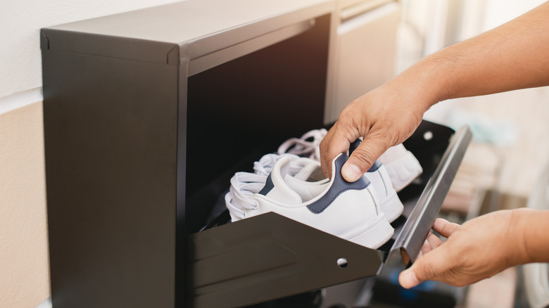 Person takes a pair of sneakers out of a shoe rack.