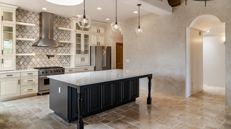 Kitchen with dark wood island, natural tile floor, and patterned backsplash