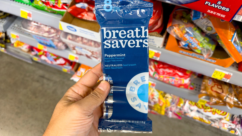 A hand holds a package of breath mints.
