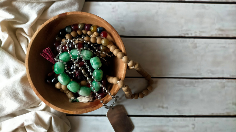 Several pieces of stone jewelry in a wooden bowl