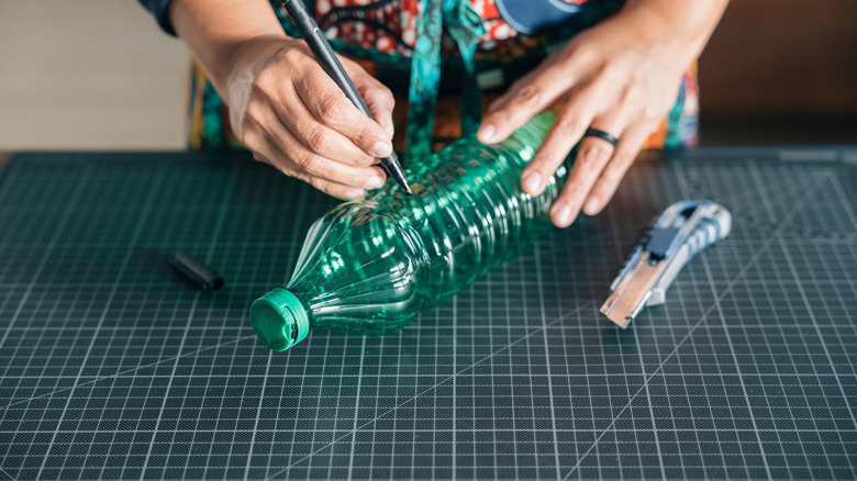 Close-up of hands cutting off the neck from a plastic bottle