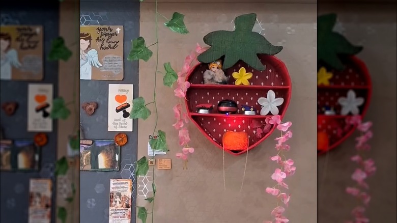 A small strawberry wall shelf holding knick-knacks