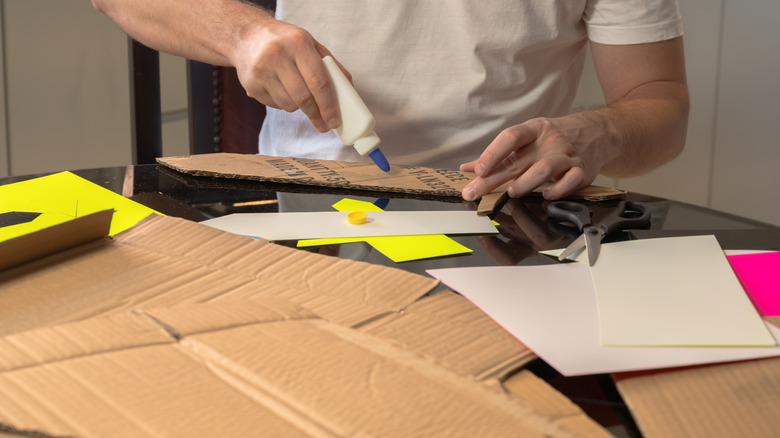 Man applying glue to the back of a piece of cardboard for a craft