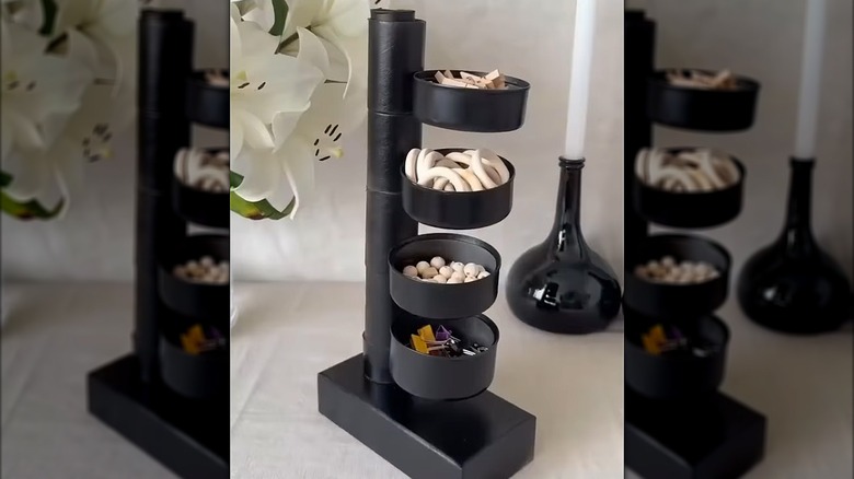 Small item organizer made of cardboard tubes and four metal tins painted black.