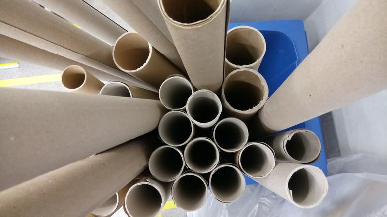 A stack of cardboard tubes in a blue plastic container
