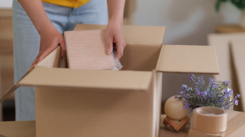 Hand placing item inside cardboard box