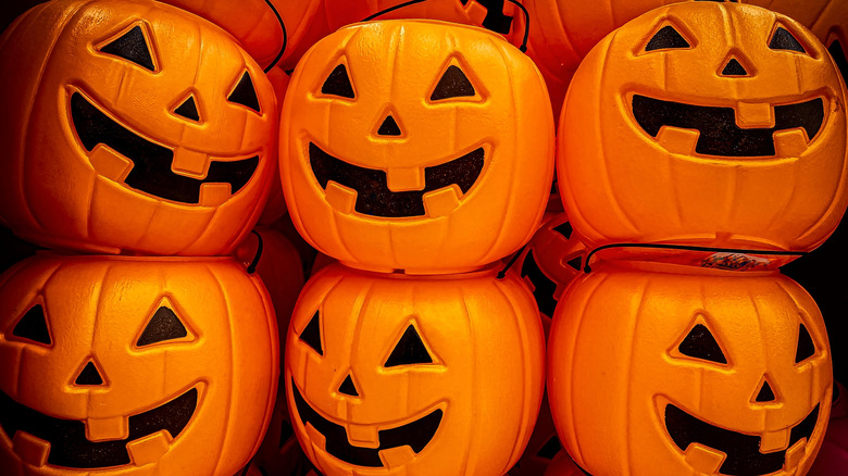 Stacks of plastic orange jack-o'-lantern candy buckets for Halloween