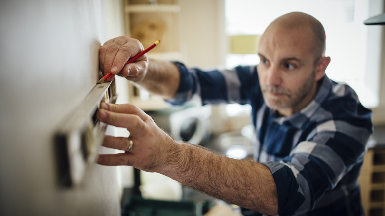 Person marking a place on the wall for a shelf