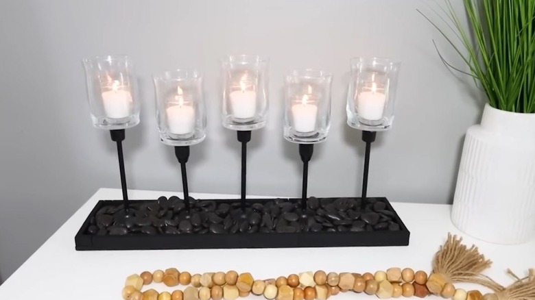A black candle centerpiece with five candles and riverstones at the base.