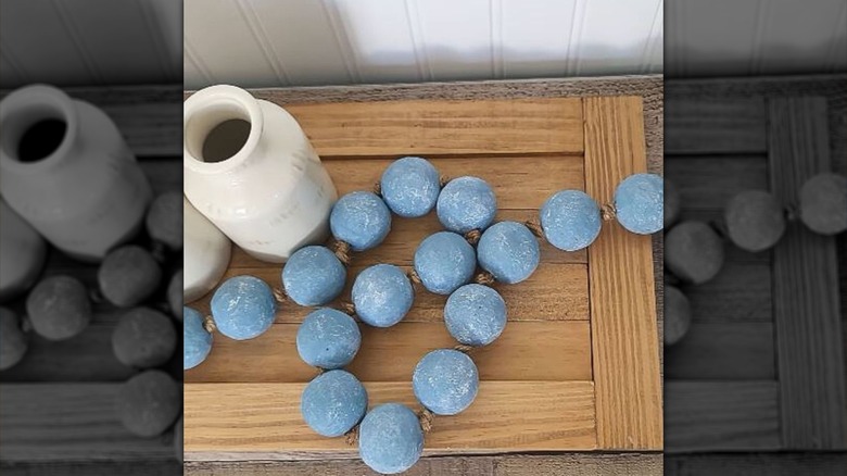 Large blue bobbles strung on decorative rope rest on a table.