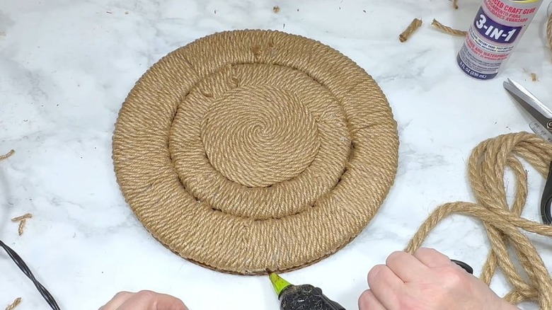 A person makes a jute placemat.
