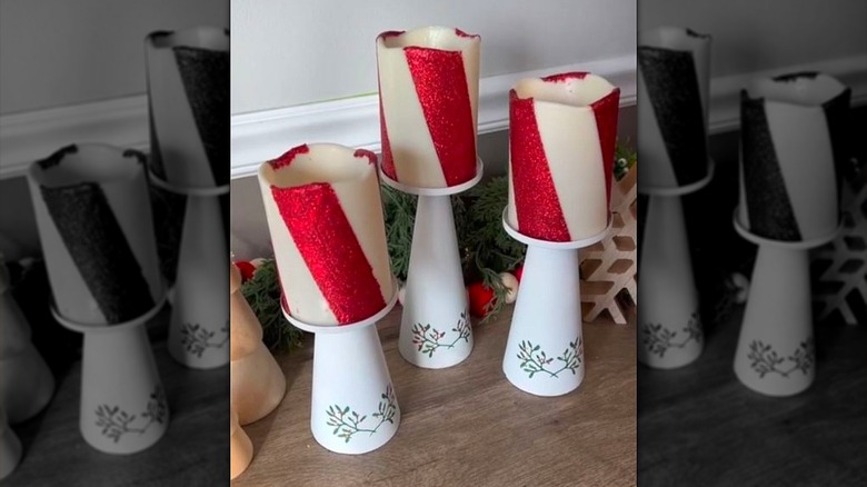 Three candy cane striped candles on white candle holders.