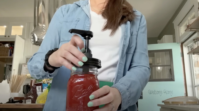 A DIYer holding a mason jar filled with ketchup