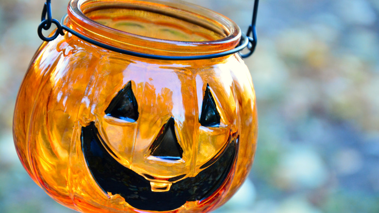 A Dollar Tree glass pumpkin hung as a lantern