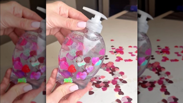 A bottle of clear soap with holographic heart shaped confetti suspended in it