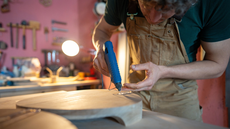 person building a DIY with hot glue
