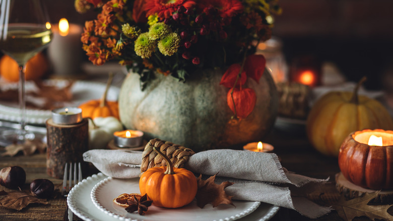 A Thanksgiving centerpiece featuring pumpkins and tealight candles