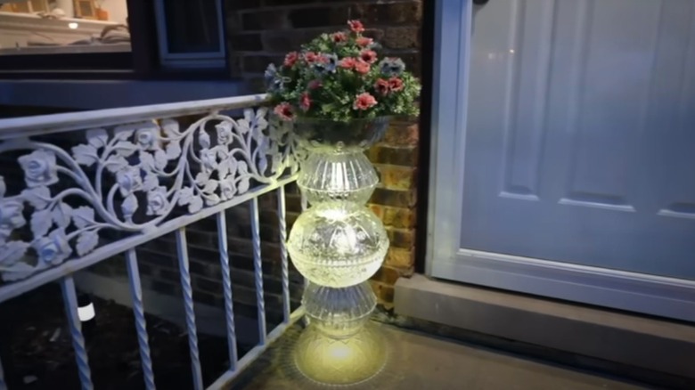 A luminary planter made from Dollar Tree plastic bowls and solar lights on a porch.