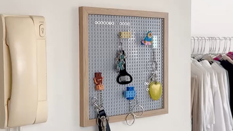 A DIY building block keyholder with a gray baseplate hanging on an entryway wall.