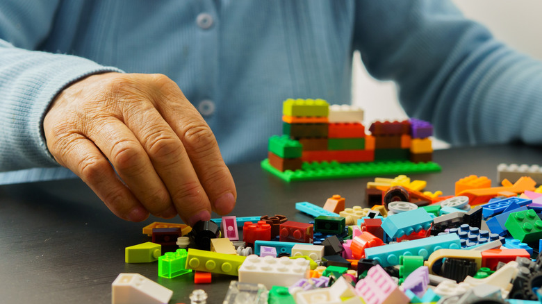 An adult sifting through piles of plastic building blocks.
