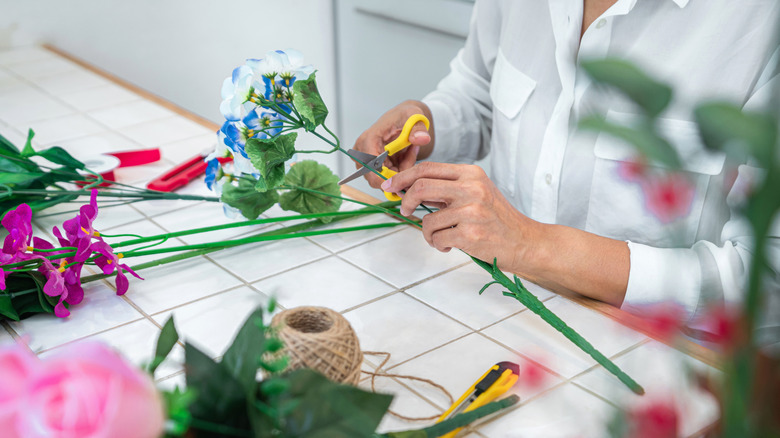 A person cuts artificial flower stems for a DIY craft project