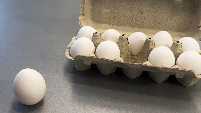 Egg carton with one egg sitting out next to it