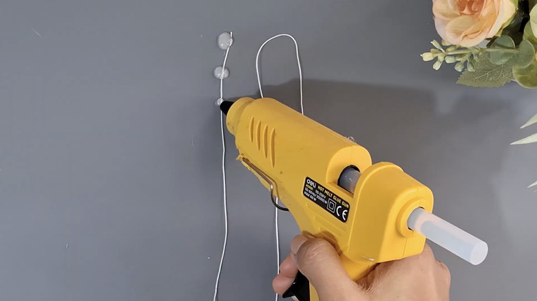 Adding dots of hot glue to a length of twine spread out on a flat tabletop.