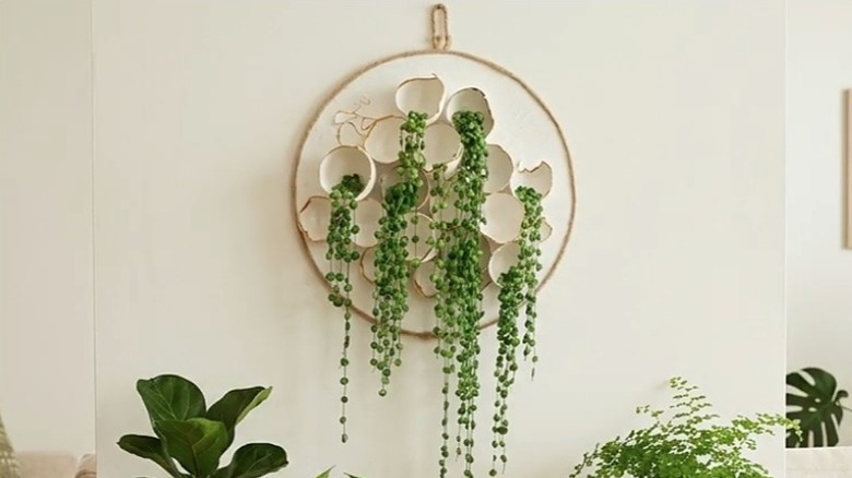 Round wall art made using a round board, eggshells, and faux string of pearls strands.