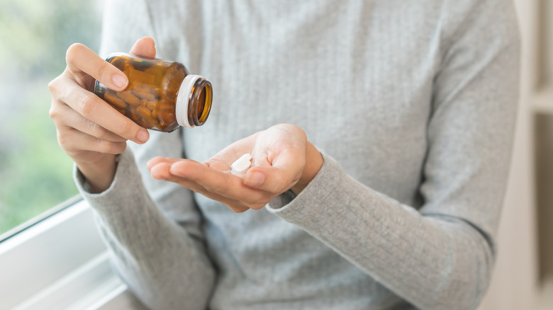 Woman pouring pills into her hand from bottle